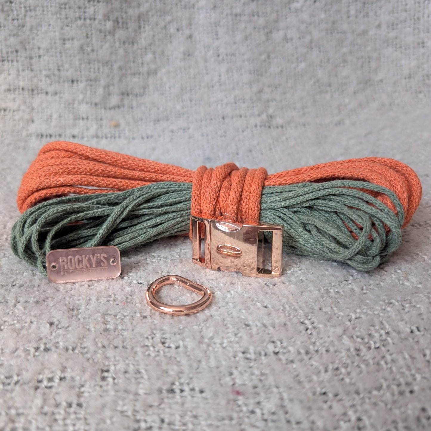 Two-colored cord with rose gold clasp and keychain on a textured gray surface